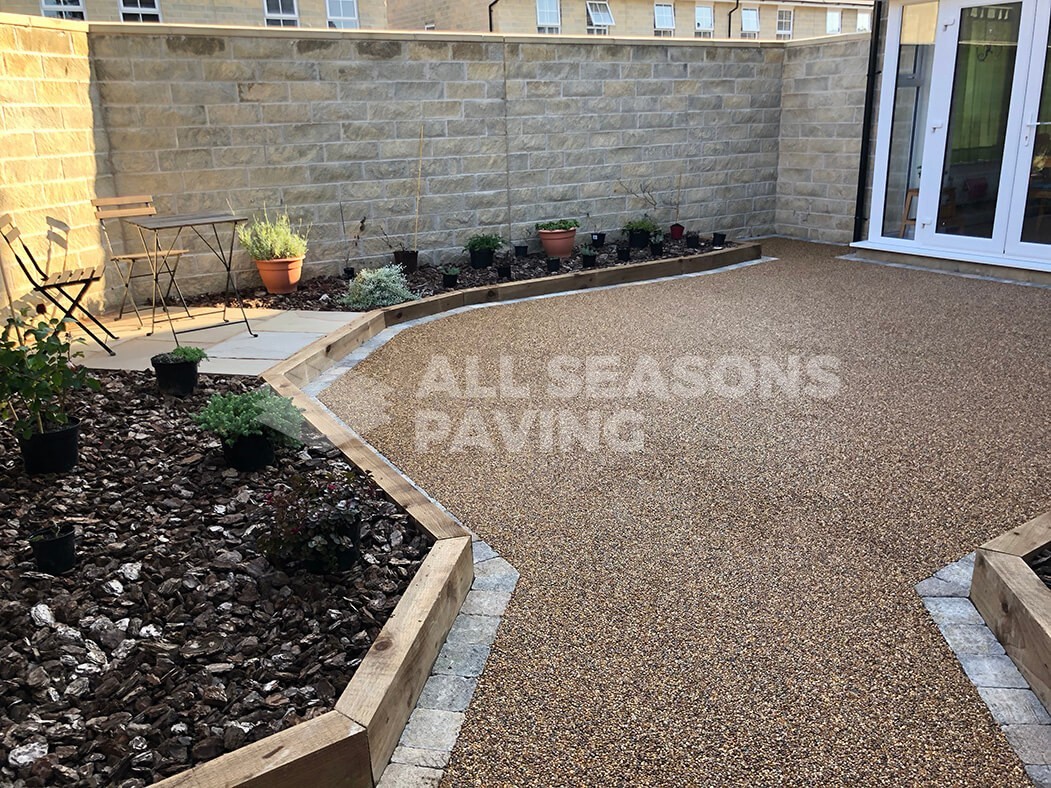 View of Resin Bound patio installed in Lancashire, near Preston showing raised flower beds and seating area.